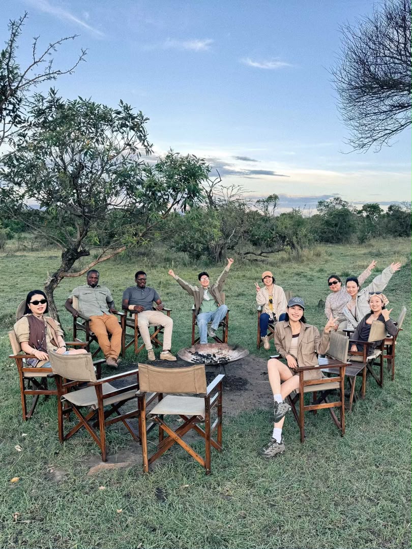 Guests seated in safari chairs under a shade tree for a bush lunch