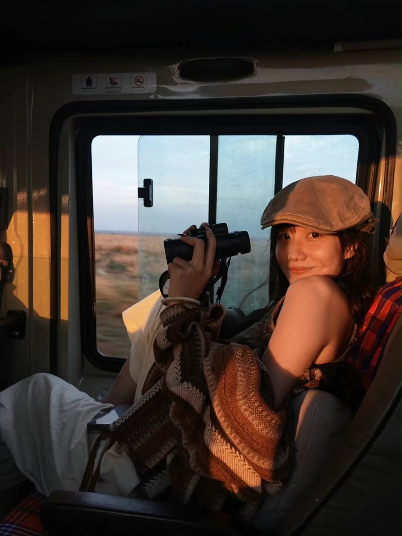 Guest scanning the plains with binoculars from a safari vehicle at sunrise