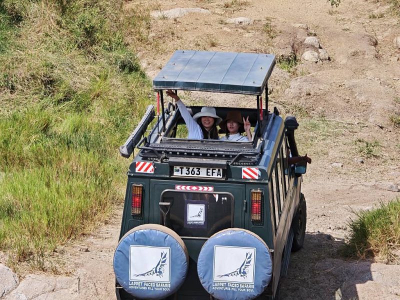 Guests waving from the roof hatch as their vehicle fords a water crossing