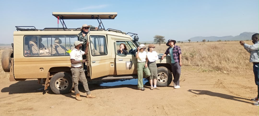 Guests standing with their guide beside the safari vehicle