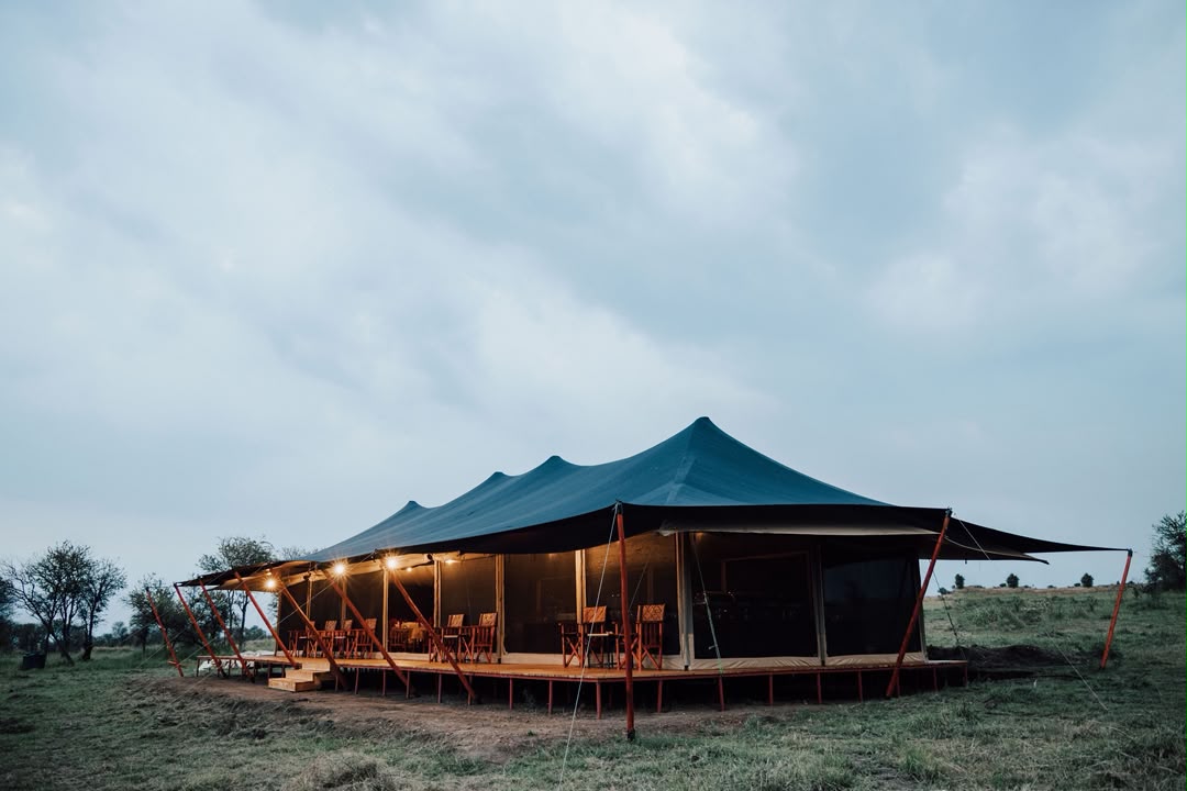 Safari tented camp with its lounge lit at dusk